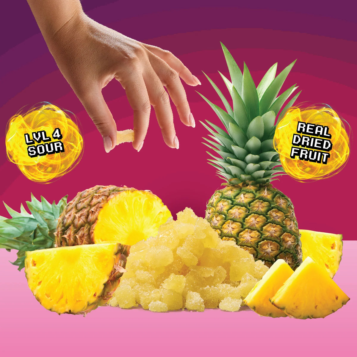 A hand reaches toward a whole pineapple and sliced pineapples arranged with crushed yellow fruit pieces on a pink and magenta gradient background. Two circular callouts read 'LVL 4 SOUR' and 'REAL DRIED FRUIT'.